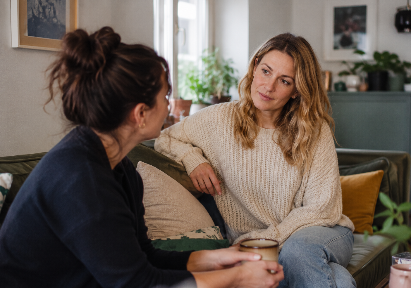 Two women having a thoughtful conversation in a relaxed home environment.